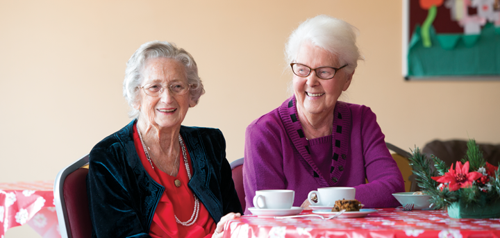 Two older women enjoying tea at a social group