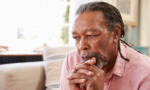 An older Black man sits looking worried