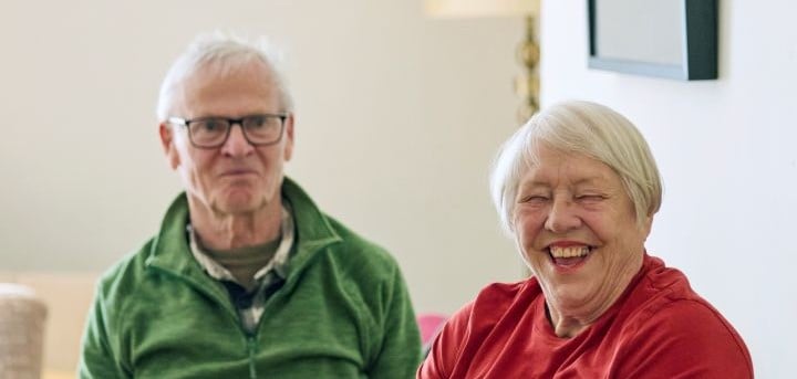 two older people laughing at the camera