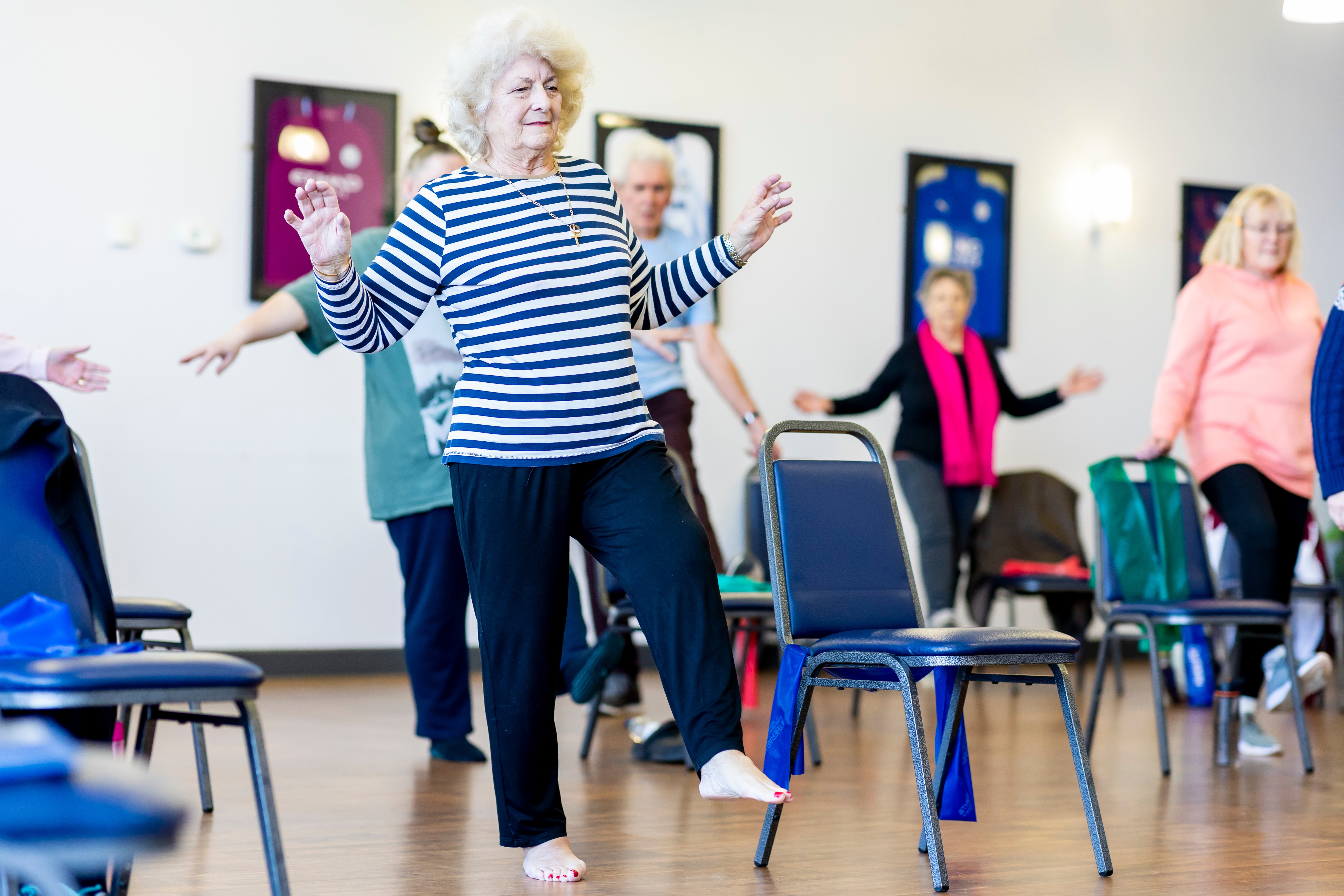 Lady standing on one leg in strength and balance class. 