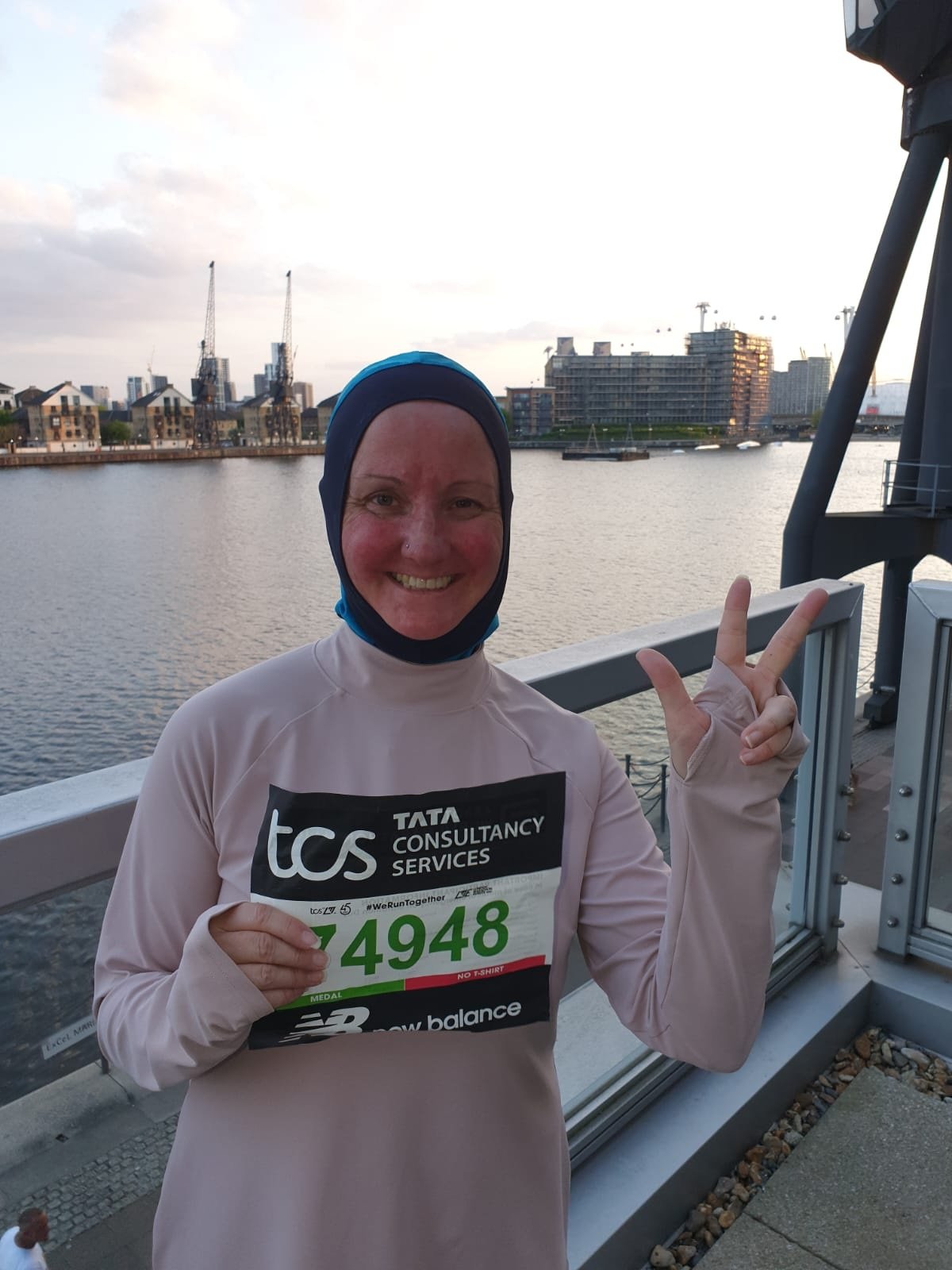 Woman smiling with River Thames in background holding race number