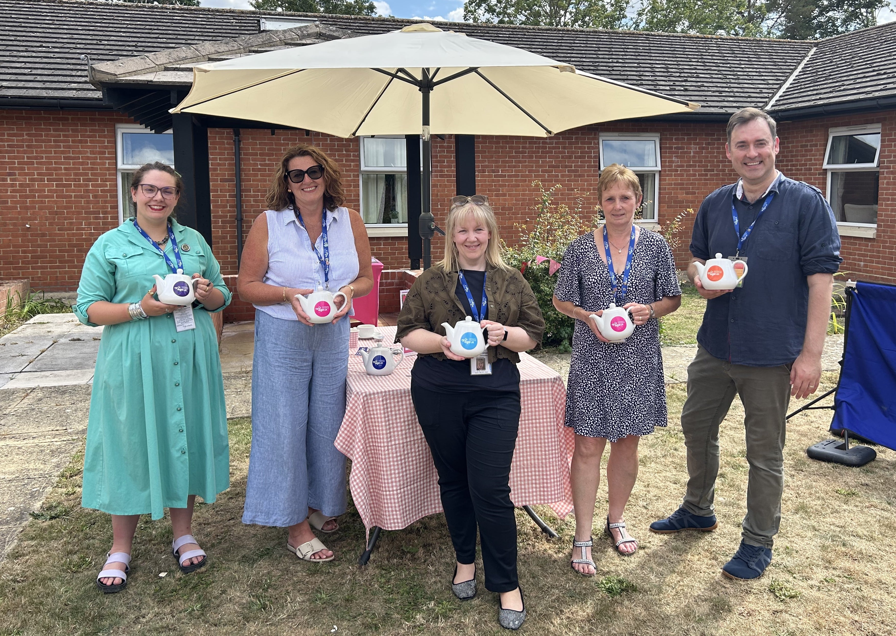 Image of Age UK CAP Staff and Supporters holding branded tea pots