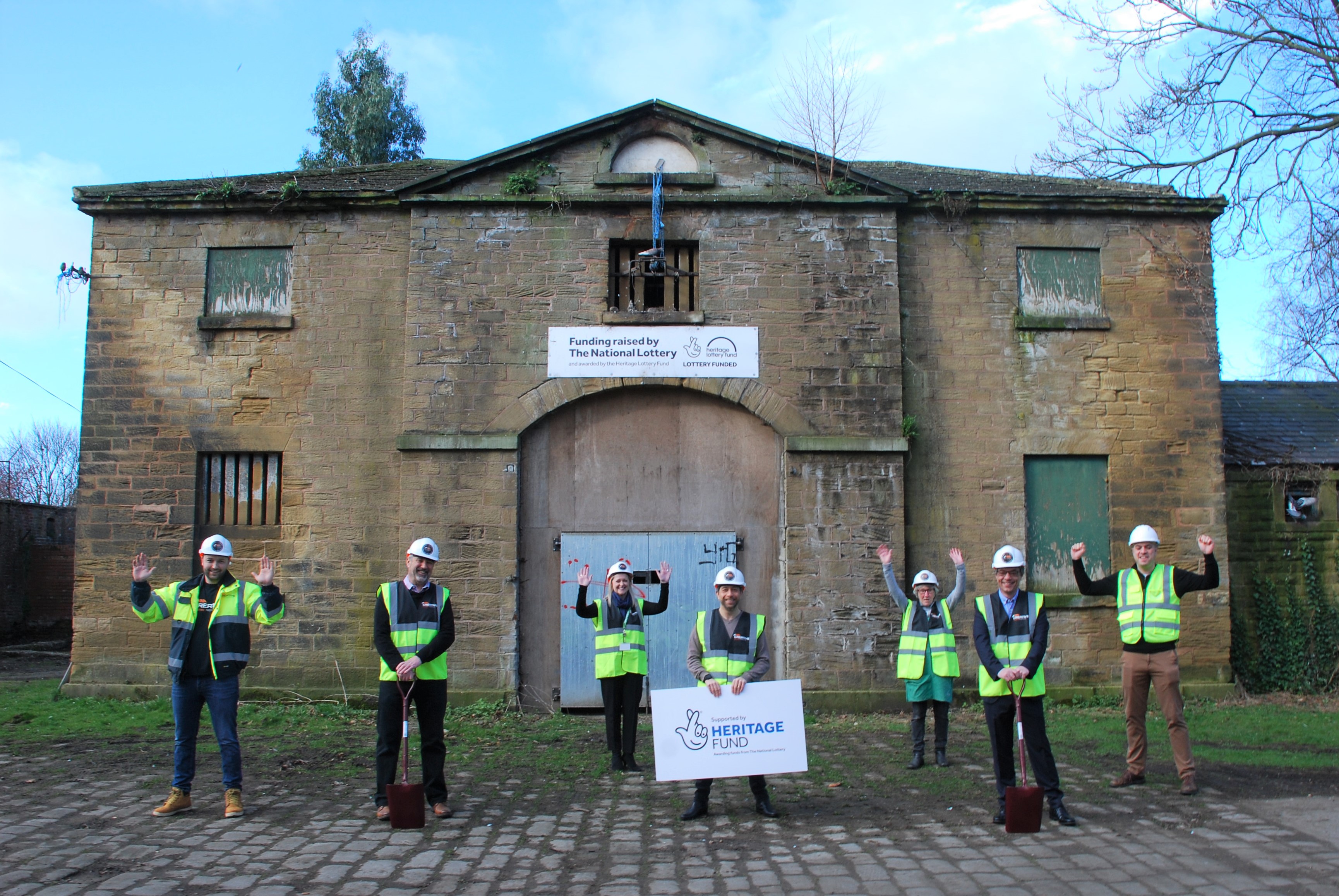 Team stands in front of Old Coach House building wearing High-vis vests and helmets 