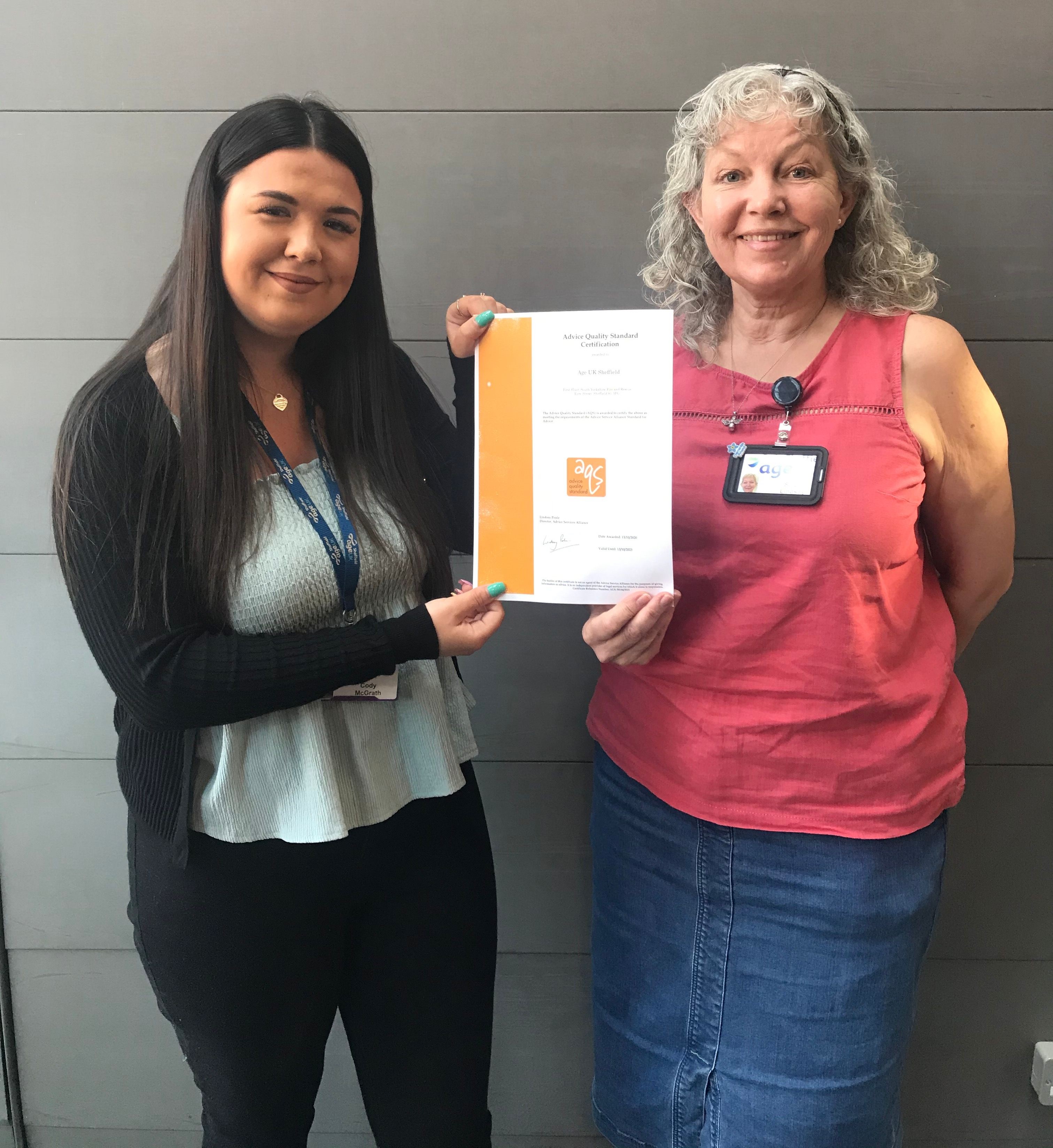 Age UK Sheffield Staff members Cody and Sarah proudly smile whilst holding the Information and Advice Quality Programme Certificate