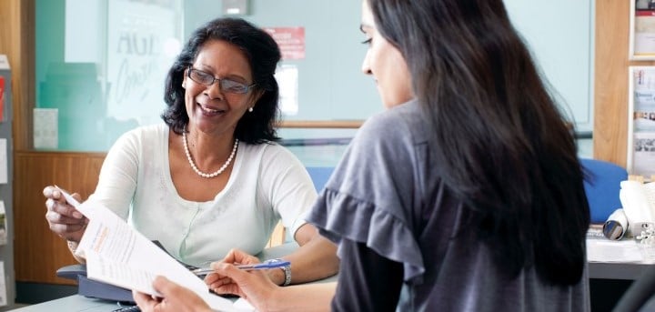 An adviser helping a woman with paper forms