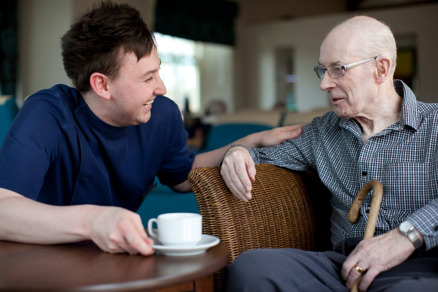 Carer with man passing him cup of tea