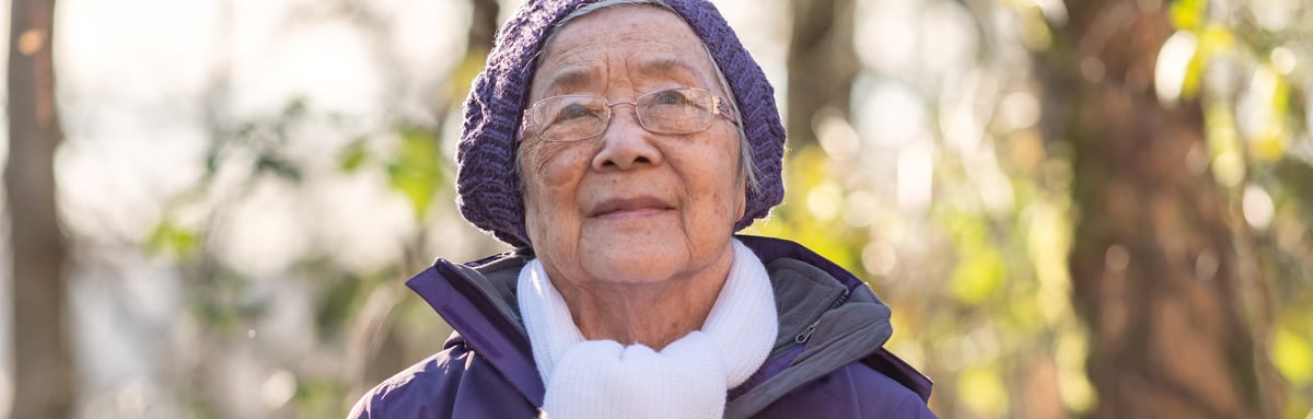 Older lady dressed in a winter coat wearing a scarf and woolly hat