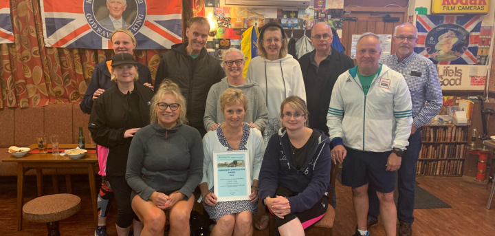 Photo showing Carol seated holding Community Appreciation Award Certificate from Werrington Neighbourhood Council and fellow club mates.