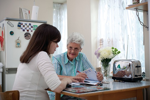 2 people sat at a kitchen table with paperwork