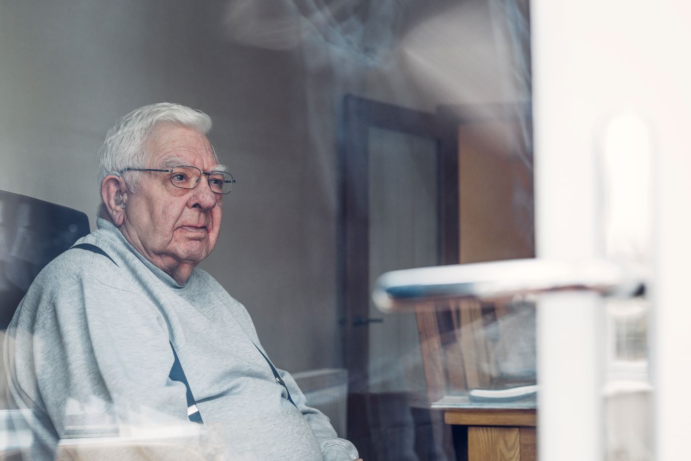 Older man sitting alone looking thoughtful – representing loneliness in later life