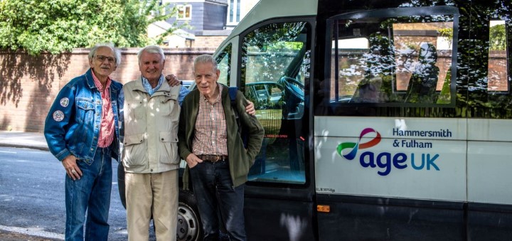 Senior gentlemen stand next to a minibus