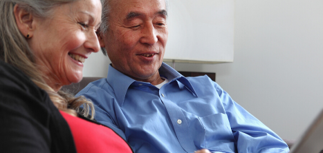 Older couple sitting close to each other smiling at an image on a laptop