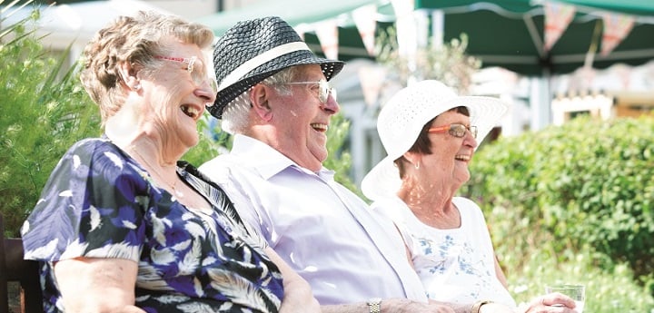 Man and two women sitting on a bench in the sunshine