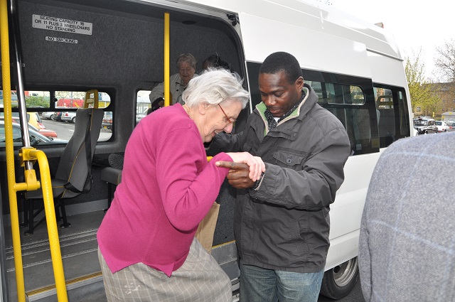Volunteer helping a lady off of a minibus