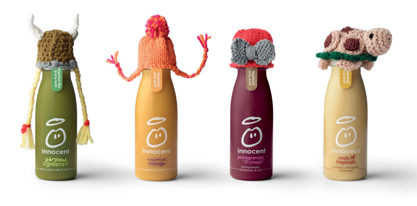 A row of Innocent Smoothie bottles each with a little knitted hat on top