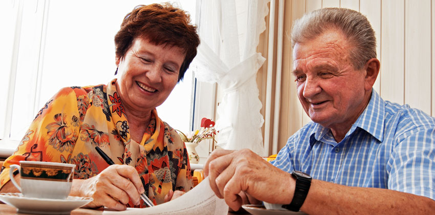 Our Triage Information Support Service a happy older man and woman sitting at a table looking at an information sheet