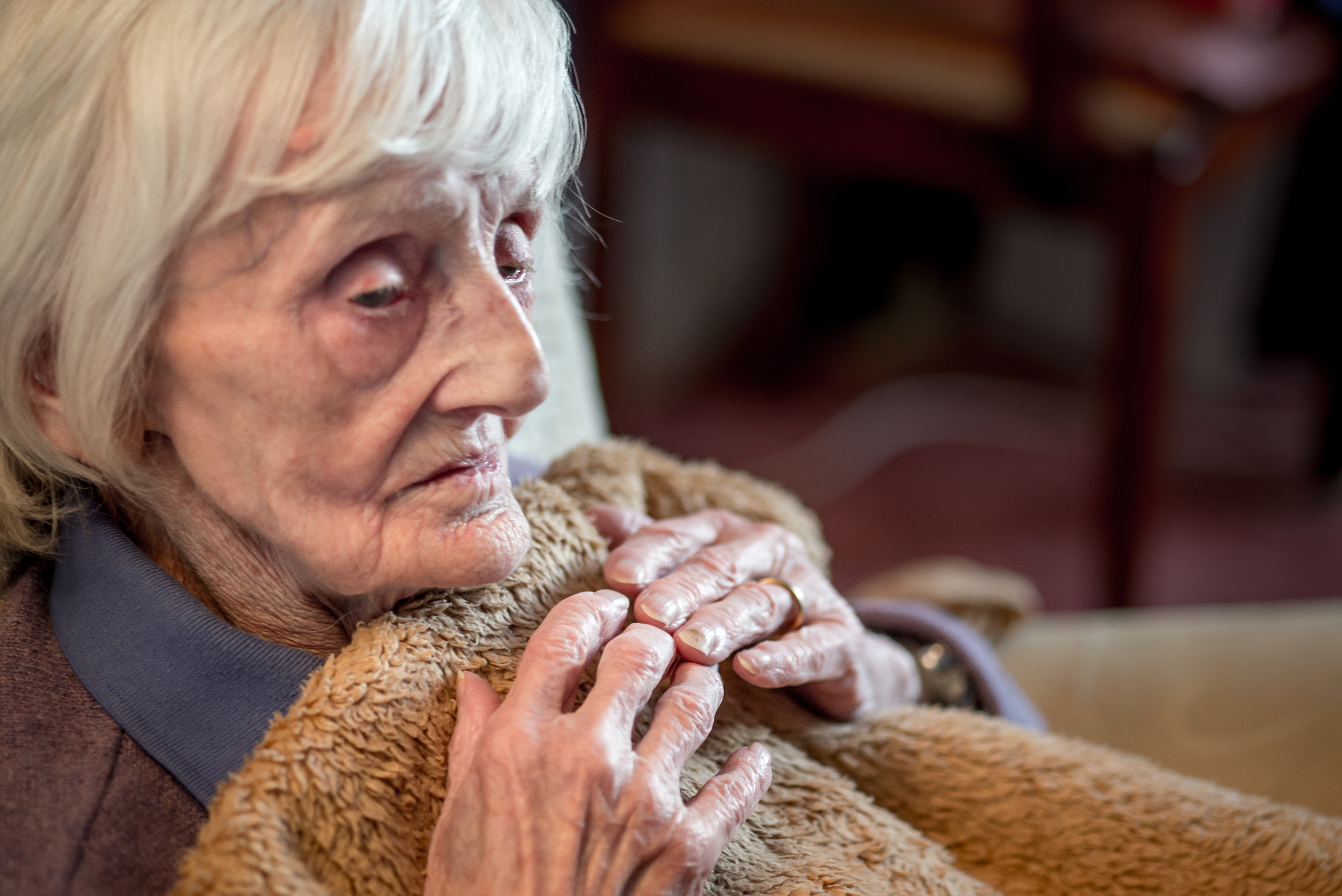 Older woman wrapped in blanket concerned about the cost of living crisis