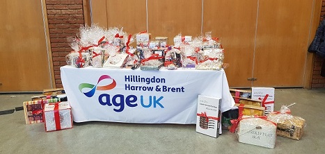 A photo of a table bearing gifts. The Age UK Hillingdon Harrow and Brent logo appears on the tablecloth