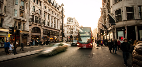 A red routemaster bus drives through a busy London street