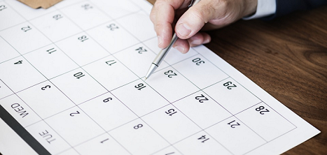 A hand filling in a calendar - your priorities