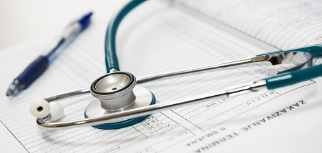 A pen and a stethoscope lie on a medical document