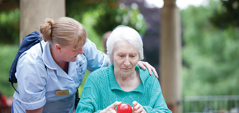A carer helping an older lady to play boules