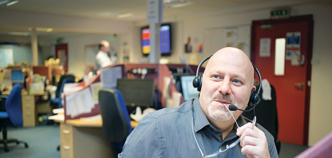 A man wearing a telephone headset in an office. 