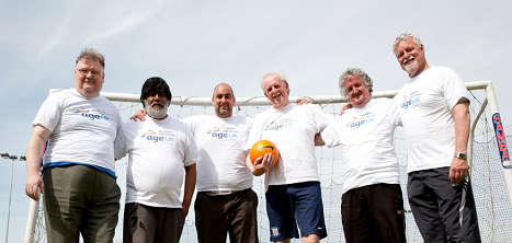 An football team of older men pose for a team photo.