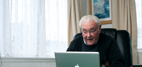 An older man using a laptop at home.