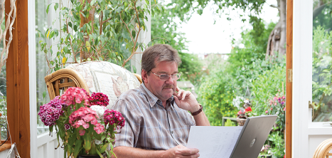 An older man looks at his laptop at home.