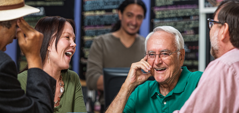 Four older people laughing in a cafe.