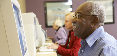 An older man happily using a computer.