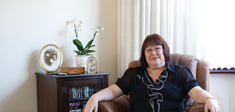 An older woman sits in her armchair facing the camera