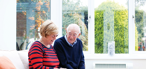 An older couple smiling on the sofa.