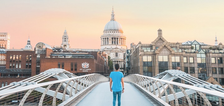 A man walks towards St Paul's Cathedral along Millennium Bridge. He is walking away from the camera.