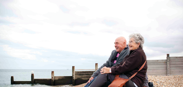 A couple sat on a pebble beach near the sea 