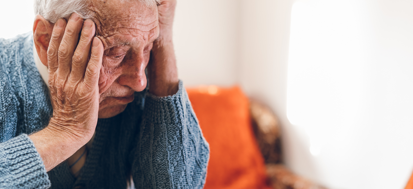 Older man with head in hands at table 