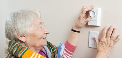 Elderly lady adjusting thermostat