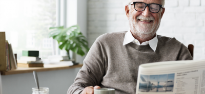 Older man reading newspaper with coffee