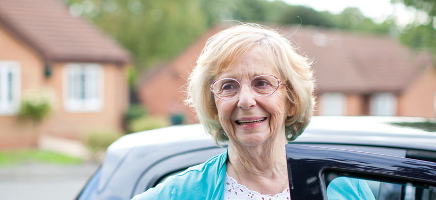 Older woman standing with her car