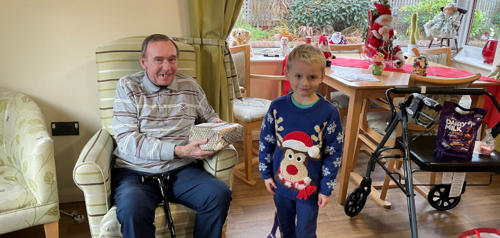 Joshua presenting a Christmas gift to a happy older person.