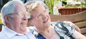 older couple sitting in garden smiling