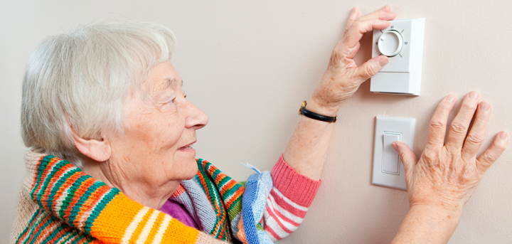 Older woman adjusting a thermostat