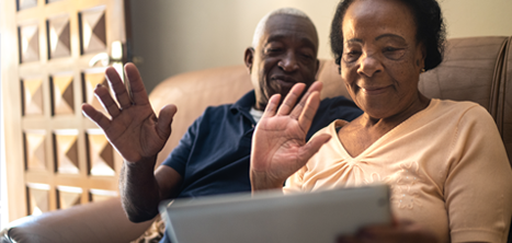 Older couple waving at a computer tablet