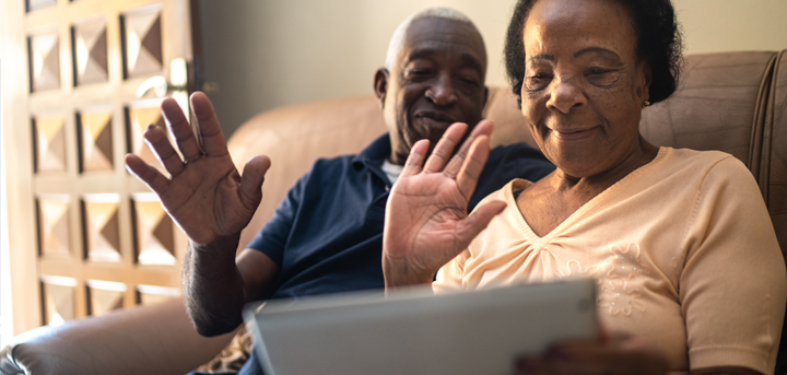 Older couple waving at a computer tablet