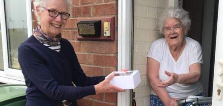 Volunteer day centre organiser presenting a day centre member with a gift during lockdown
