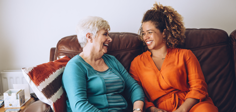 Two women sitting on a sofa and laughing