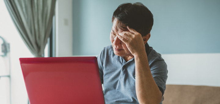 An unhappy older man using a laptop