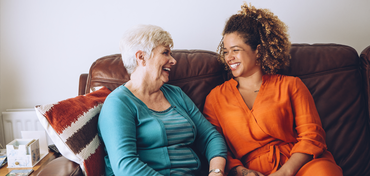 Two women sitting on a sofa and laughing