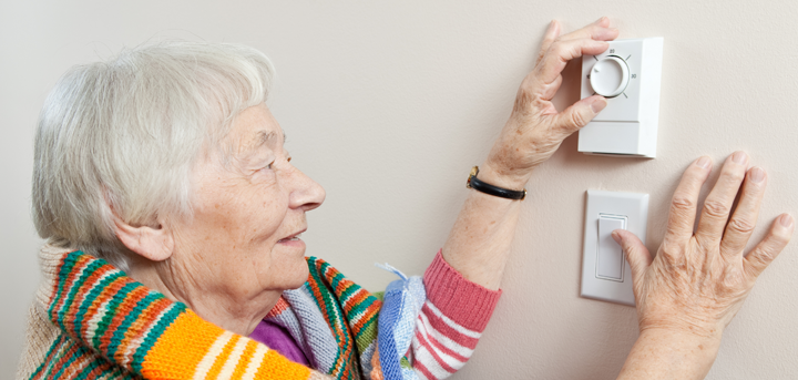 Older woman adjusting a thermostat